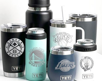 Puede incluir: Una colección de recipientes aislados para bebidas con logotipos de equipos deportivos. Incluye una botella de agua negra, vasos y enfriadores de latas. Logotipos: Denver Nuggets, Golden State Warriors, New York Knicks, Los Angeles Lakers y Boston Celtics.