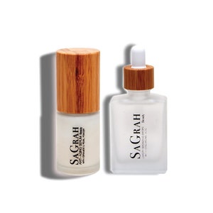 K&ouml;nnte beinhalten: Zwei Glasflaschen mit Bambusverschl&uuml;ssen, die Hautpflegeprodukte enthalten. Die Flasche links ist mit "SAGRAH ANTI-AGING SERUM Beauty WITH CERAMIDE & PEARL POWDER" beschriftet. Die Flasche rechts ist mit "SAGRAH LUKUR BRONZING DROPS Beauty WITH HYALURONIC ACID" beschriftet.
