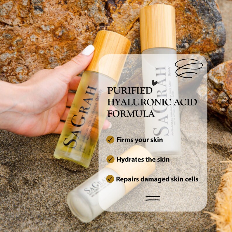 May include: Three brown glass bottles with bamboo caps and white labels. The labels have the text "SAGRAH" and "PURIFIED HYALURONIC ACID FORMULA". The bottles are on a sandy beach background. The text "Firms your skin", "Hydrates the skin", and "Repairs damaged skin cells" is also visible.
