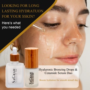 K&ouml;nnte beinhalten: Zwei Glasflaschen mit Bambusverschl&uuml;ssen und Etiketten mit der Aufschrift "SAGRAH", die Hautpflegeprodukte enthalten. Die Flaschen sind mit "Luxury Bronzing Drops" und "Anti-Aging Serum" gekennzeichnet. Der Text "Hyaluronic Bronzing Drops & Ceramide Serum Duo" wird unter den Flaschen angezeigt. Der Text "Boosts hydration for smooth skin all day" wird unter den Produktnamen angezeigt.