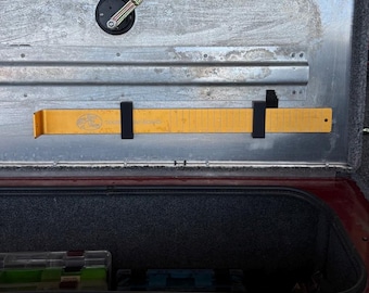 May include: A yellow measuring ruler with black brackets attached to the side of a truck bed. The ruler has the words "Fish On" and "Catch & Release" printed on it.