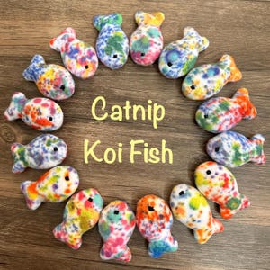 May include: A circle of 15 colorful catnip koi fish toys. The toys are made of soft, fuzzy fabric with a white base and colorful spots. The text "Catnip Koi Fish" is written in yellow letters in the center of the circle.