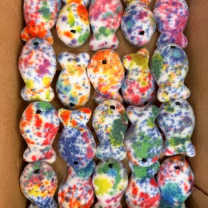 May include: A box filled with 20 colorful tie-dye fish plush toys. The fish are all white with different colored spots and swirls.