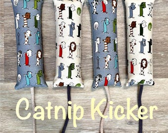 May include: Four rectangular catnip kickers with animal print fabric in blue, white, and cream. Each kicker has a different animal pattern and a rope tail. The text "Catnip Kicker" is displayed in a cursive font.