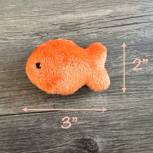 Pode incluir: Um brinquedo de pel&uacute;cia de peixe dourado laranja que mede 7,6 cm de comprimento e 5 cm de altura.