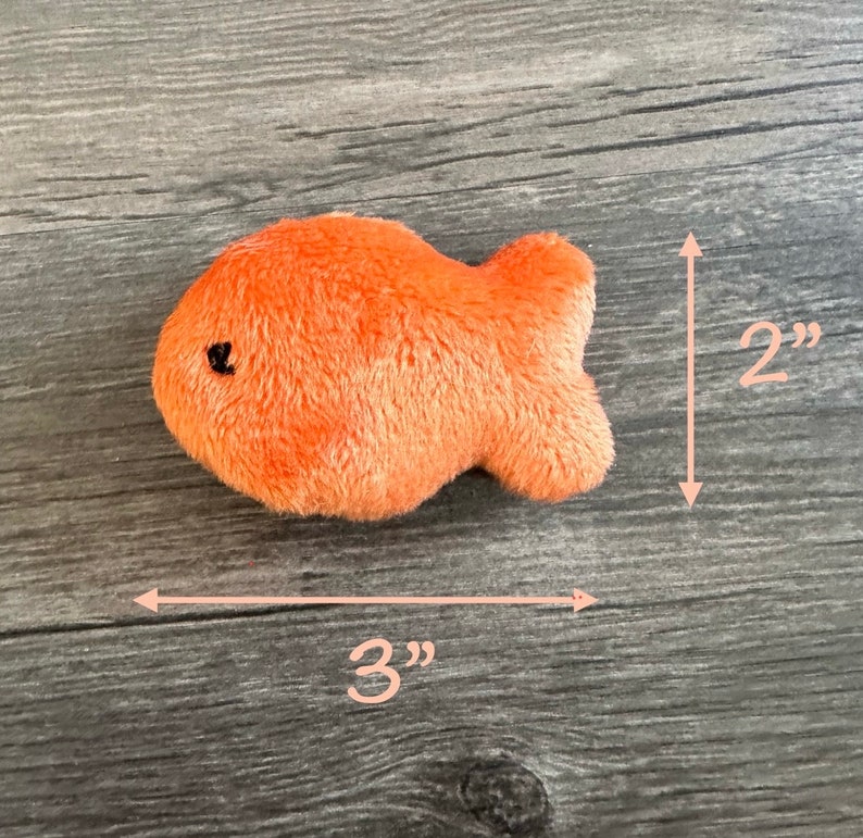 Pode incluir: Um brinquedo de pel&uacute;cia de peixe dourado laranja que mede 7,6 cm de comprimento e 5 cm de altura.
