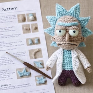 May include: A crocheted Rick doll with a light blue spiky hair, a white lab coat, and a light blue shirt. A crochet pattern sheet and a crochet hook are next to the doll. The text "Crochet Pattern" is visible.