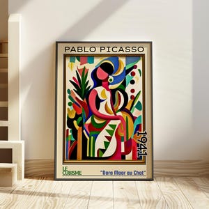 Może przedstawiać: Oprawiony wydruk artystyczny "Dora Maar au Chat" Pablo Picasso z 1941 roku. Grafika przedstawia siedzącą kobietę w kapeluszu, oddaną w żywych kolorach i stylu kubistycznym. Wydruk jest w czarnej ramie.