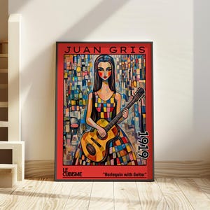 以下が含まれることがあります： 「Harlequin with Guitar」というタイトルの、フアン・グリスによるキュビズム絵画の額装されたアートプリント。ギターを持つ女性が描かれ、カラフルな背景が特徴です。フレームの右側には1919年の文字があります。