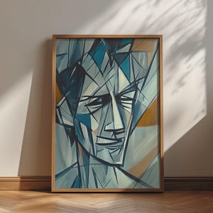 May include: A framed rectangular wall art print featuring a stylized portrait composed of sharp, angular geometric lines. The color palette consists of various shades of blue, grey, and muted ochre, creating a fragmented, abstract human face.