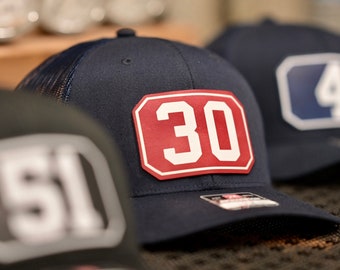 May include: Three navy blue mesh trucker hats with red and white number patches. The numbers on the hats are 30, 4, and 51.