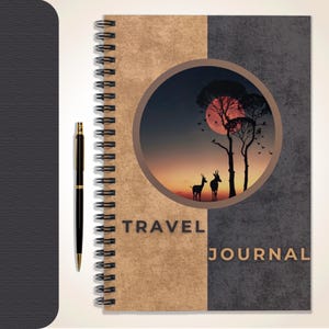 May include: Spiral-bound travel journal with a two-tone cover, featuring a nature scene in a circular frame. The journal has the words "TRAVEL JOURNAL" printed on the cover. A black pen rests beside the journal.