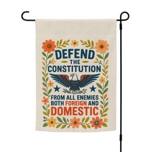 Könnte beinhalten: Eine cremefarbene Gartenflagge mit dem Text "DEFEND THE CONSTITUTION FROM ALL ENEMIES BOTH FOREIGN AND DOMESTIC." Die Flagge zeigt einen blauen Adler, Sterne und florale Akzente in Orange, Gelb und Grün.