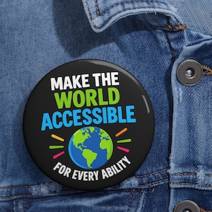 以下が含まれることがあります： MAKE THE（白）、WORLD（緑）、ACCESSIBLE（青）のテキストが書かれた黒い円形のピンバッジ。下部には青と緑の地球のグラフィックがあり、白いテキストでFOR EVERY ABILITYと書かれ、カラフルなアクセントラインが添えられています。