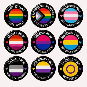 May include: A set of nine circular pin-back buttons featuring various pride flags. Each button has a black border with white text and small colored hearts. The flags include rainbow, progress, transgender, lesbian, bisexual, pansexual, asexual, non-binary, and intersex designs with slogans like Love Is Love, Progress Not Perfection, and Born Perfect.