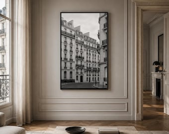May include: A rectangular black-framed wall art print featuring a black and white photograph of a Parisian street scene with multi-story stone buildings, wrought iron balconies, and a curved road leading into the distance under a cloudy sky.