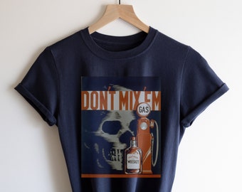 以下が含まれることがあります： 「Don't Mix 'Em」と書いてある、ヴィンテージスタイルのグラフィックプリントが施されたネイビーブルーのTシャツ。プリントには、骸骨、ウイスキーのボトル、ガソリンスタンドのポンプが描かれている。グラフィックは赤、オレンジ、白で構成されている。
