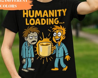 May include: Black t-shirt with the text "HUMANITY LOADING..." in yellow. The shirt features a cartoon illustration of two figures, one looking tired and the other holding a coffee cup. The words "12 DIFFERENT COLORS" are in an orange box.