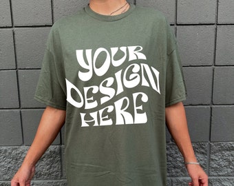 Può includere: Una maglietta verde con il testo "YOUR DESIGN HERE" in bianco, in lettere stilizzate.