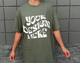 May include: A green t-shirt with the text "YOUR DESIGN HERE" in white, stylized lettering.