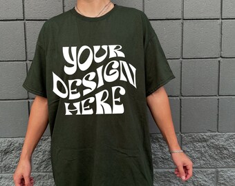 Può includere: Una maglietta verde scuro con la scritta "YOUR DESIGN HERE" stampata in bianco sul davanti.