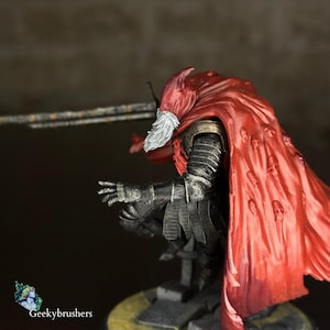 May include: A detailed miniature figure of a warrior in dark armor, a red cape with skull designs, and a white beard. The figure is holding a sword and is posed in a battle stance. The figure is on a stone base.