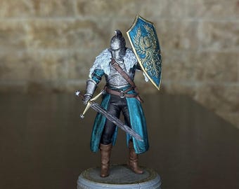 May include: A miniature figurine of a knight in silver armor, holding a sword and a shield with a gold emblem. The knight wears a teal tunic and a fur-lined collar. The figurine stands on a decorative base.