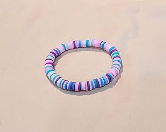 May include: A colorful bracelet made of small, round, flat beads in shades of pink, purple, blue, and white.