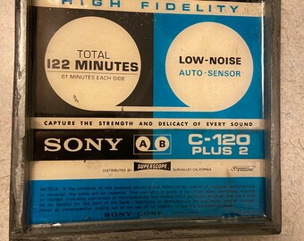 Op de afbeelding: Een vintage audiocassetteband met het label "SONY C-120 PLUS 2 HIGH FIDELITY" met een totale opnametijd van 122 minuten. De cassette is blauw en wit met de tekst "LOW-NOISE AUTO-SENSOR" aan de rechterkant.