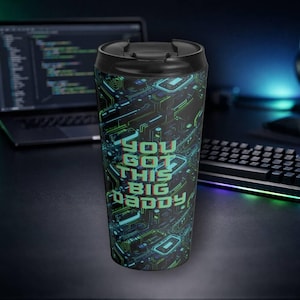 May include: Black travel mug with a circuit board design in teal and green. The mug has the text "YOU GOT THIS BIG DADDY" in a bold, neon green font. The mug is on a desk with a laptop and keyboard in the background.