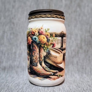 May include: White mason jar with a brown lid and a rope design. The jar has a colorful floral design with cowboy boots and a cowboy hat.
