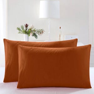 May include: Two rust-colored pillowcases with a smooth, soft texture. The pillowcases are made of a high-quality fabric and are perfect for adding a touch of color to your bedroom.