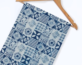 May include: A white fabric with a blue and white geometric pattern. The fabric is folded and hanging on a wooden hanger.