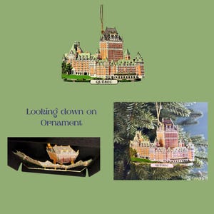 May include: A gold-colored Christmas ornament depicting the Chateau Frontenac hotel in Quebec City. The ornament is hanging from a Christmas tree branch. The ornament has the word "QUEBEC" printed on the base.