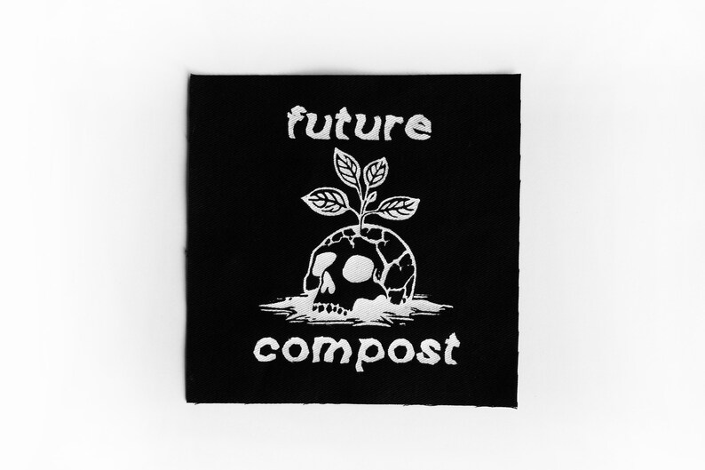 Pu&ograve; includere: Toppa nera con testo e grafica bianchi. Il testo recita "future compost". La grafica &egrave; un teschio con una pianta che cresce dalla cima.