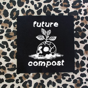 Pu&ograve; includere: Toppa termoadesiva nera con testo e grafica bianchi. Il testo recita "future compost" e la grafica &egrave; un teschio con una pianta che cresce dalla cima.