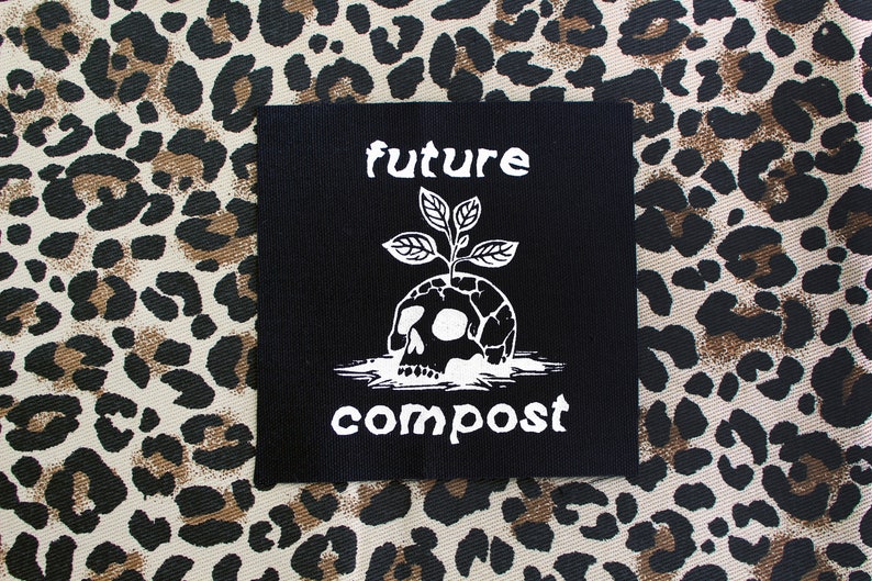 Pu&ograve; includere: Toppa termoadesiva nera con testo e grafica bianchi. Il testo recita "future compost" e la grafica &egrave; un teschio con una pianta che cresce dalla cima.