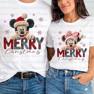 May include: White t-shirts featuring Mickey and Minnie Mouse wearing Christmas hats. The shirts display the text "MERRY Christmas" in red and green plaid letters. Festive snowflakes are also printed on the shirts.