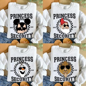 Op de afbeelding: Vier lichtgrijze sweatshirts met lange mouwen, elk met een ander stripfiguur met een zonnebril. De tekst "PRINCESS SECURITY" staat op elk shirt, met "SINCE 2026" eronder.