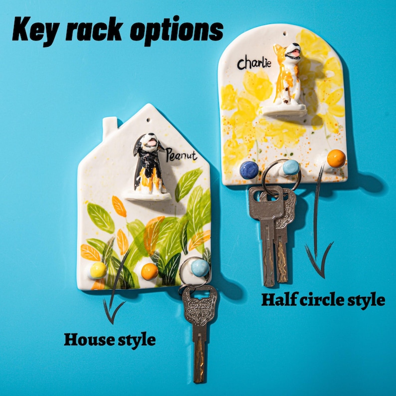 May include: Two ceramic key racks in house and half-circle styles, each with a dog figurine. The house-shaped rack has the name "Peanut" and the half-circle rack has the name "Charlie". The text "Key rack options" is at the top.