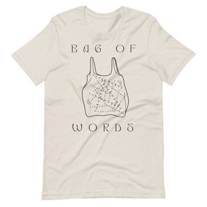 May include: A beige t-shirt with a black graphic of a plastic bag filled with words and the text "BAG OF WORDS" printed on the front.