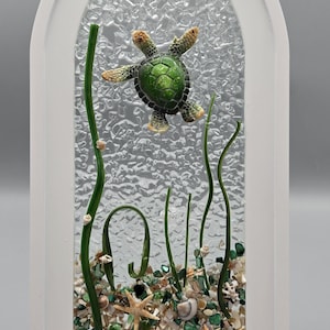 Item 187 - Green turtle on a large white arch frame.