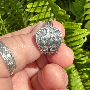 Puede incluir: Anillo de cuchara de plata con un vaquero montando un caballo salvaje. El anillo está grabado con las palabras "Buckaroo" y "Classic".