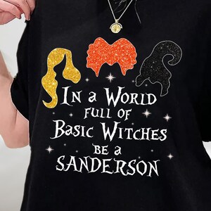 May include: Black t-shirt with a glittery graphic of three witches with the text "In a world full of basic witches be a Sanderson".