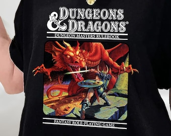 Może przedstawiać: Czarny T-shirt z grafiką Dungeons & Dragons przedstawiającą czerwonego smoka i wojownika. Grafika jest odtworzeniem klasycznego pudełka gry Dungeons & Dragons. Tekst na grafice brzmi "Dungeons & Dragons", "Dungeon Masters Rulebook" i "Fantasy Role-Playing Game".