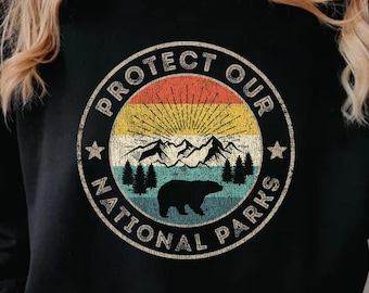 May include: Black sweatshirt with a vintage-style graphic print that says "Protect Our National Parks". The graphic features a bear, mountains, and a sun.