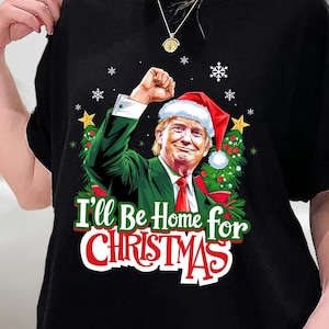 クリスマスには家に帰るよシャツ、ドナルド・トランプシャツ、クリスマストランプTシャツ、ユーモラスなトランプクリスマスシャツ、サンタトランプシャツ、スウェットシャツ、パーカー
