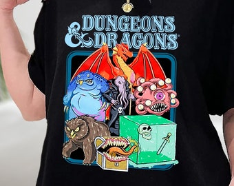 Może przedstawiać: Czarny T-shirt z grafiką przedstawiającą planszę do gry Dungeons & Dragons z czerwonym smokiem, niebieskim potworem, fioletowym potworem, brązową sową, skrzynią i zieloną kostką.