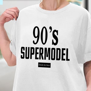Può includere: Maglietta bianca con testo nero che dice "90's Supermodel" e "Made in Italy".