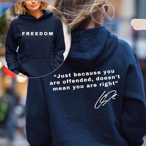 Op de afbeelding: Marineblauwe hoodie met het woord "FREEDOM" in het wit op de voorkant. De achterkant van de hoodie toont de quote, "Just because you are offended, doesn't mean you are right" in het wit, samen met een handtekening.